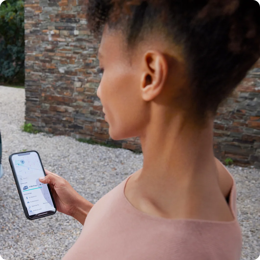Een persoon gebruikt de Free2Move Charge-app op een smartphone, voor routeplanning en begeleiding naar laadpunten voor de Citroën ë-C3 Van.