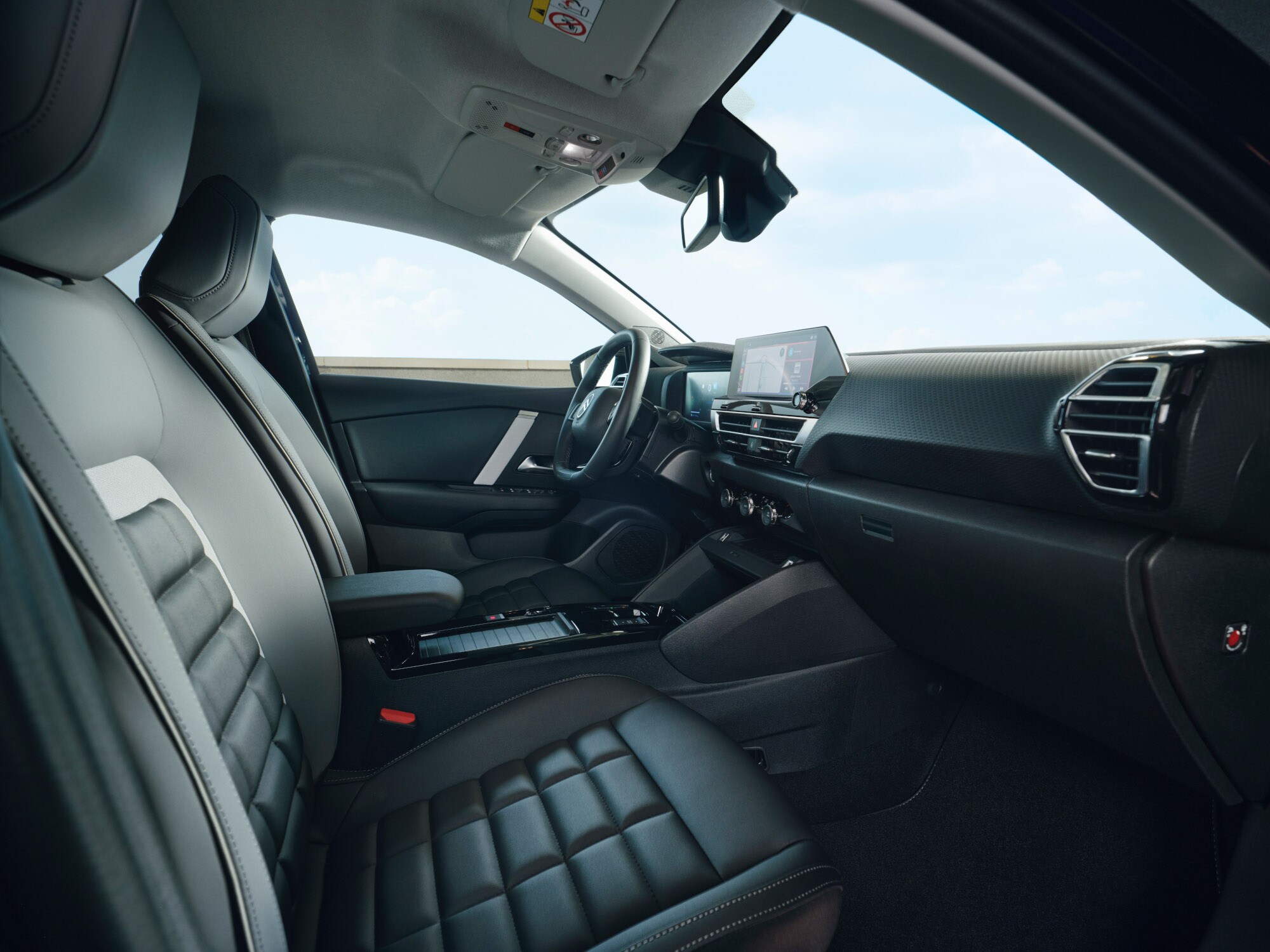 Interieuraanzicht voorin van de Citroën ë‑C4 X met stoelen, dashboard en centraal display.